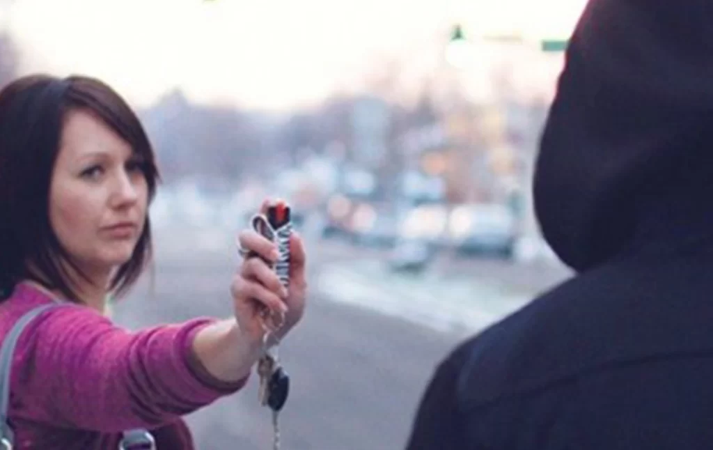 A woman spraying pepper spray to a man in the street